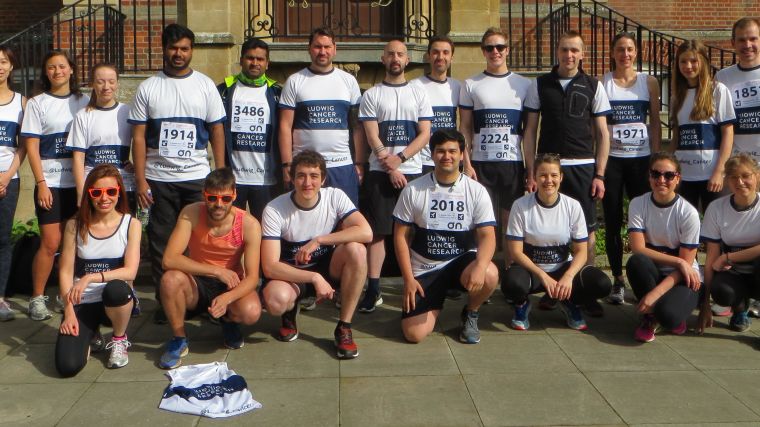 Ludwig Oxford runners posing for a photo taken before the Town and Gown race in front of the steps of the Dunn School of Pathology, wearing their matching Ludwig Cancer Research running tops